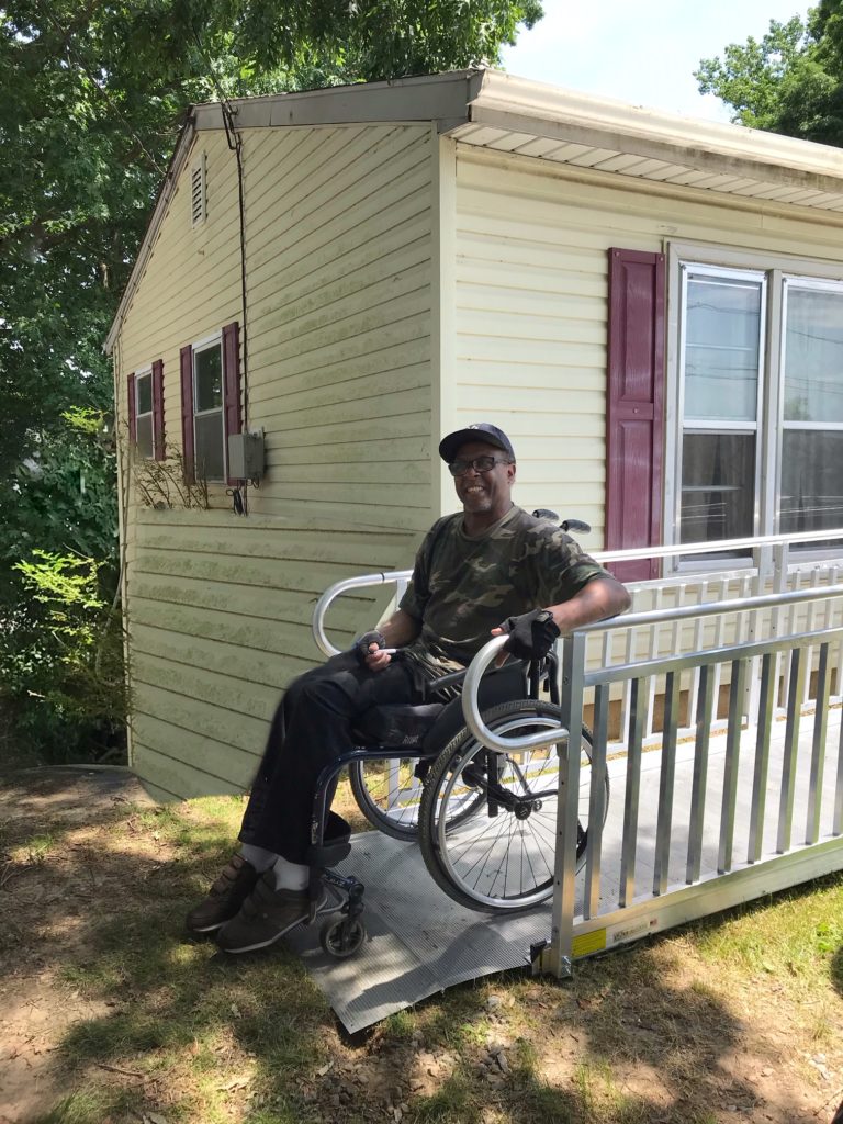 a man uses a ramp to get his wheelchair out of the house